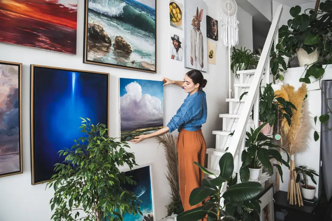 A woman hangs art on a wall - London Canvas blog post on mixing traditional and modern wall art