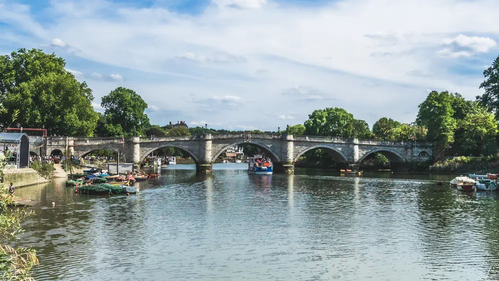 wall art for living room featuring stone bridge over calm river surrounded by trees